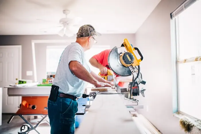 A contractor working with a mitre saw in a room mid-renovation