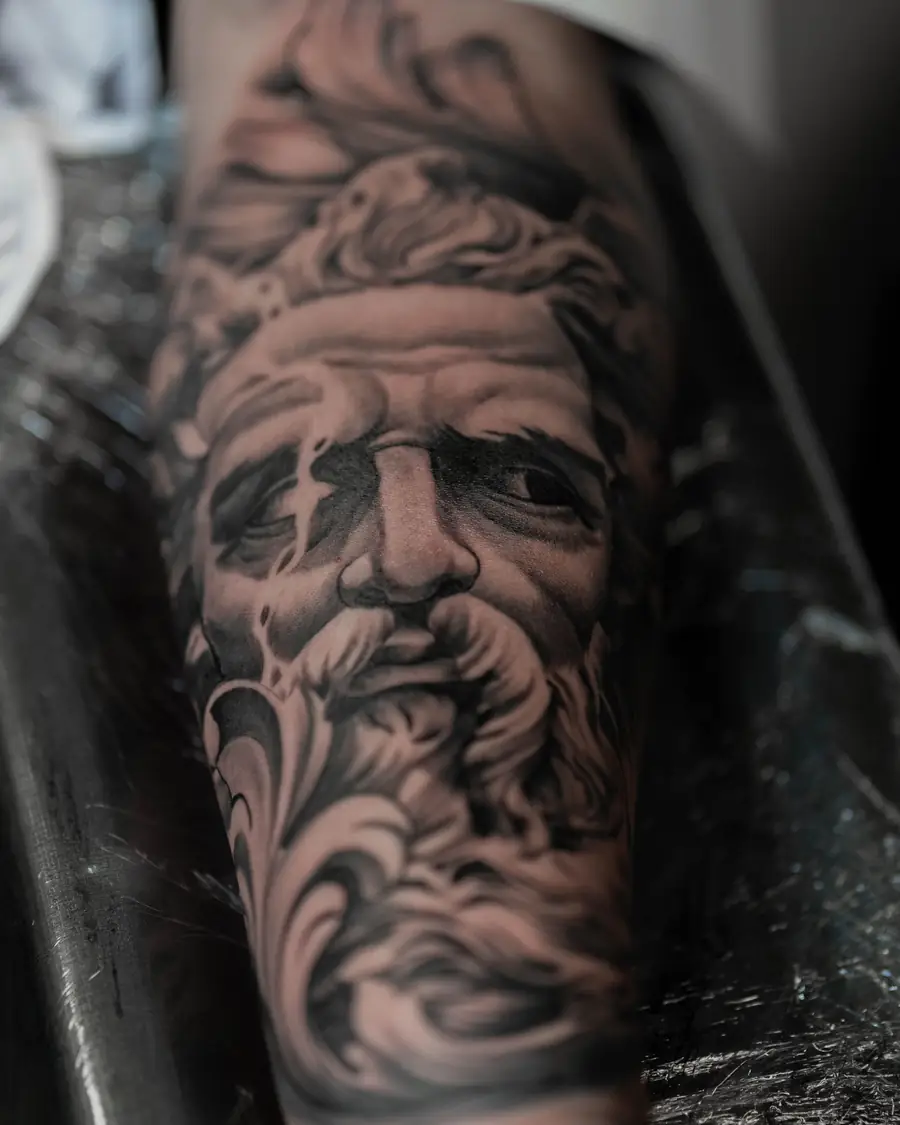 Black and grey realism portrait of a bearded man on the forearm
